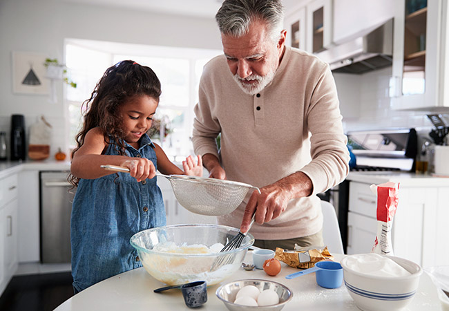 mature man and young girl baking cookies in the kitchen